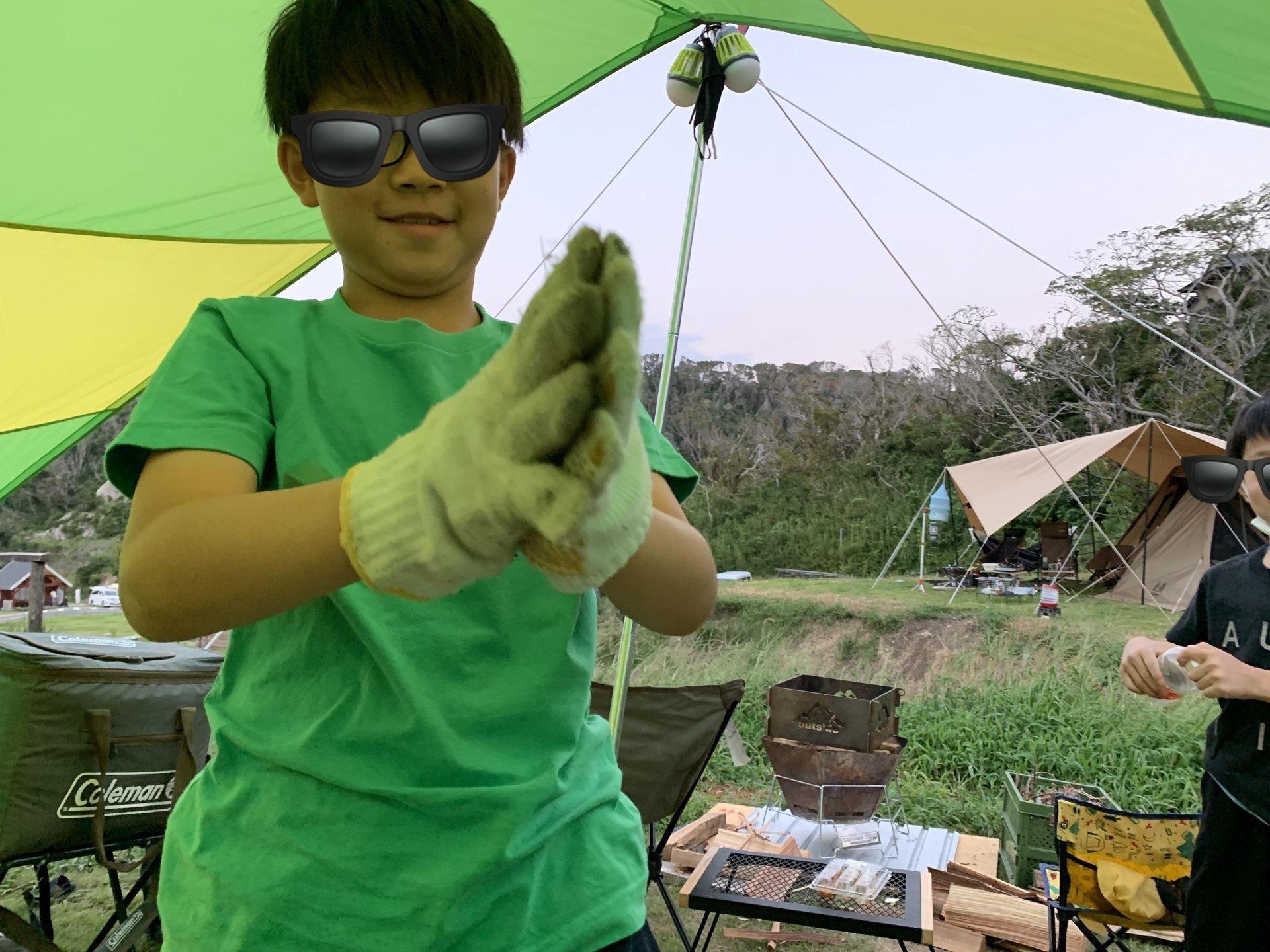 タープ下で軍手をする子とキャンプギア。海や低地では日よけのタープが快適さの生命線です