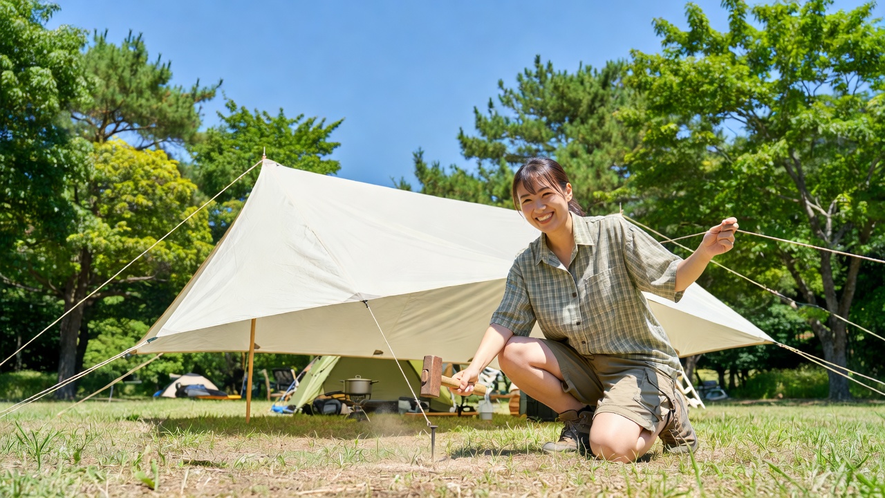 遮光タープを夏のキャンプ場で設営する様子
