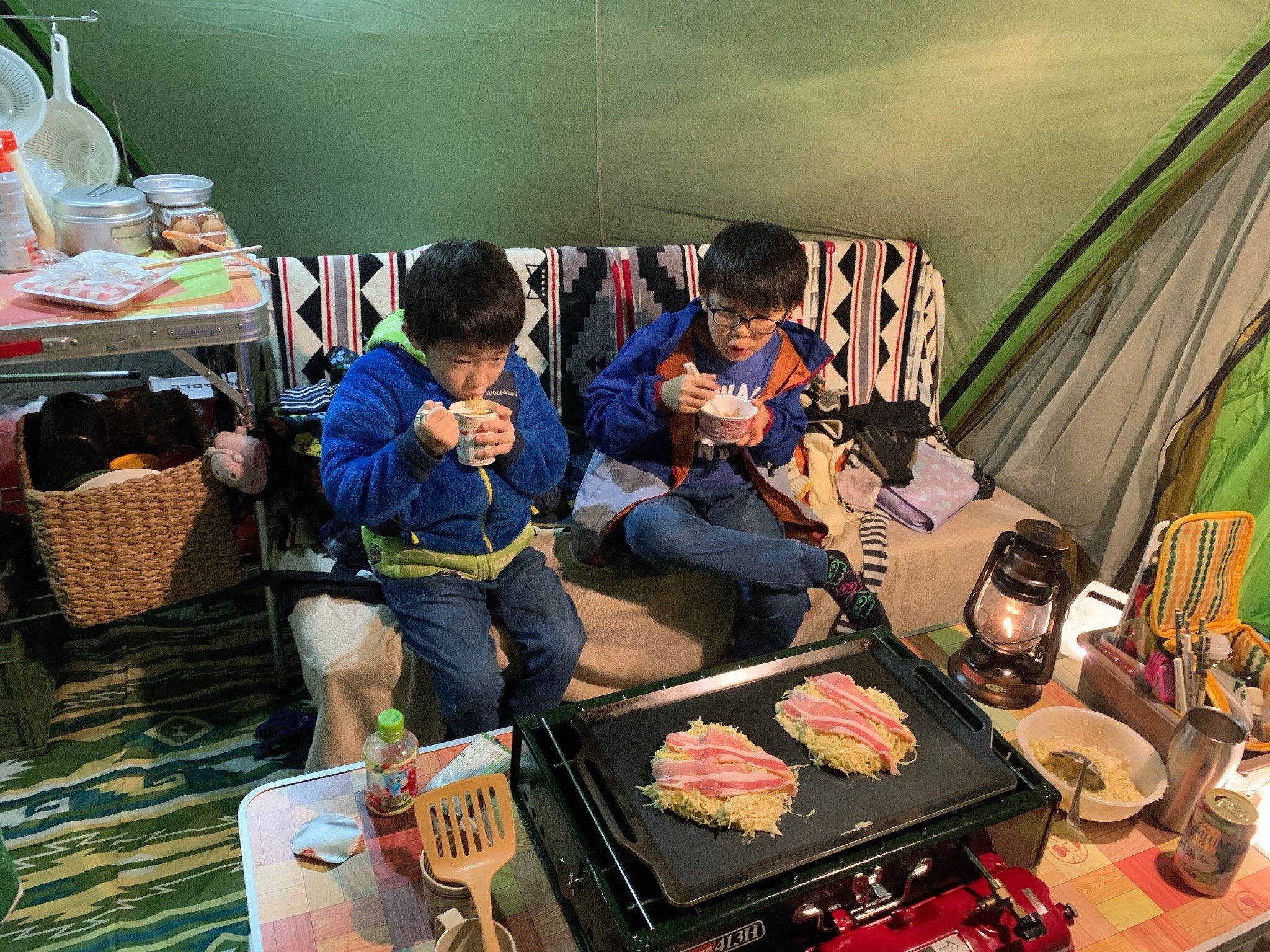 シェルターの中でツーバーナーと鉄板でお好み焼きを焼く